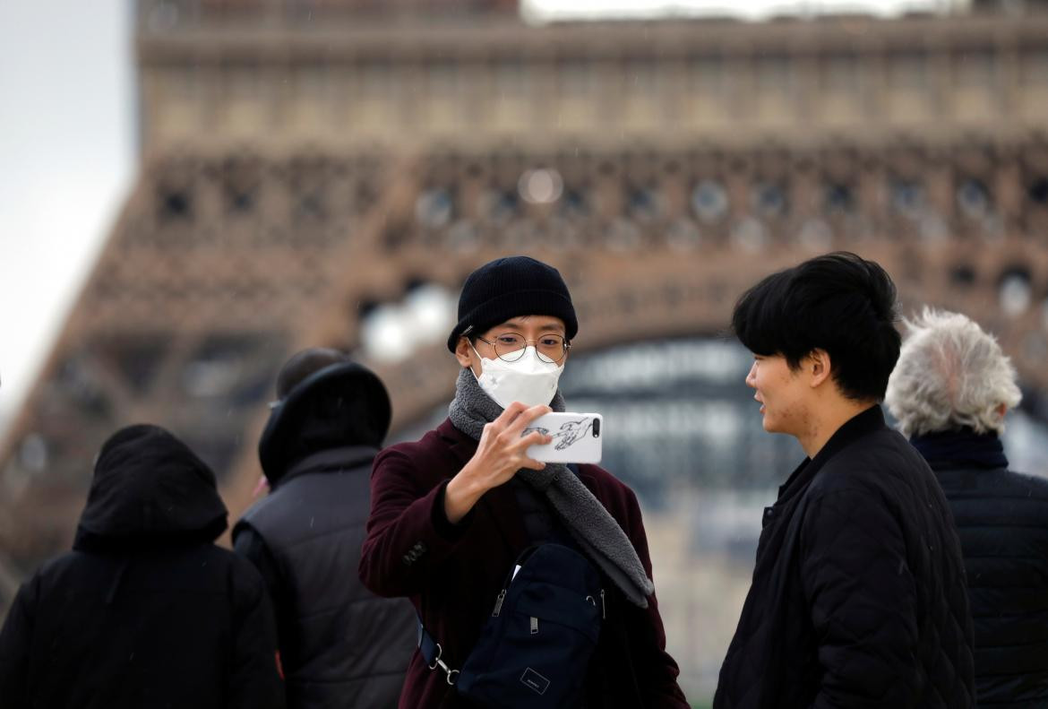 Personas con barbijo frente a la Torre Eiffel por coronavirus, REUTERS