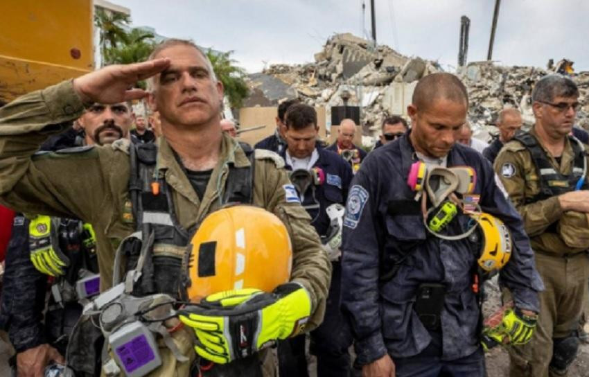 Miembros de un equipo de búsqueda y rescate durante momento de silencio frente a los escombros en Champlain Towers South.