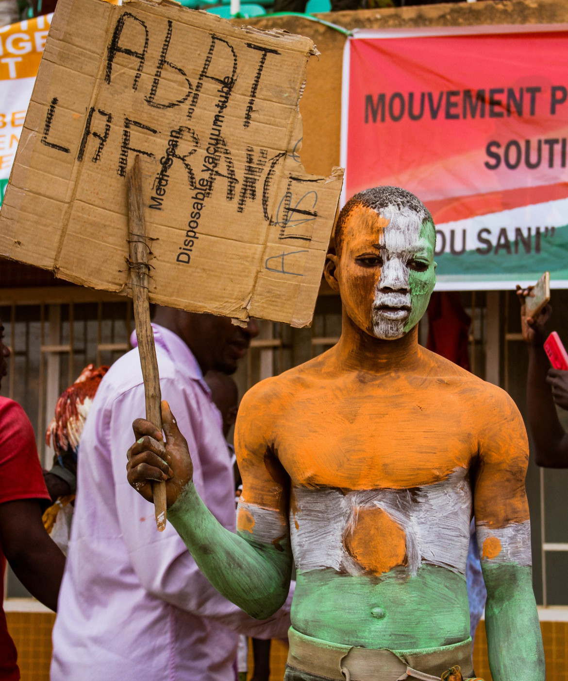 Un partidario de los líderes golpistas de Níger sostiene un cartel que dice Derribar a Francia durante un mitin en un estadio en Niamey, Níger. Foto Reuters