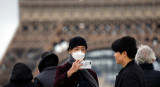 Personas con barbijo frente a la Torre Eiffel por coronavirus, REUTERS