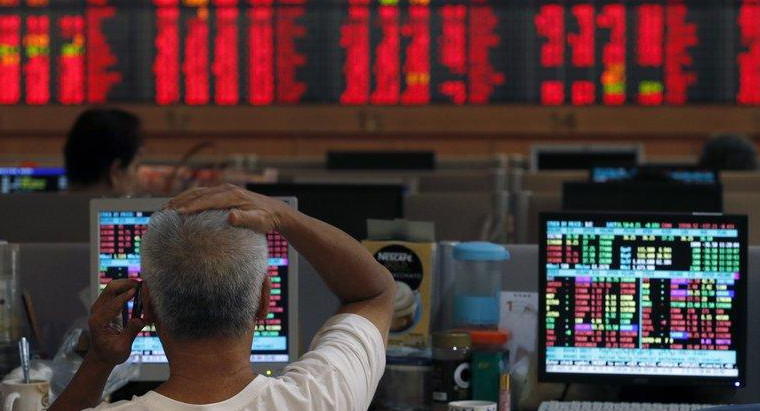 Un operador de Wall Street con pantallas en rojo de fondo, acciones