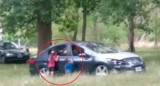 Niños fuera de un auto con sus padres dentro en el Parque Pereyra Iraola