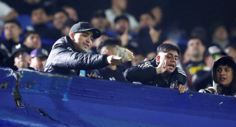 Hinchas chilenos rompiendo billetes argentinos en los estadios. Foto: REUTERS.