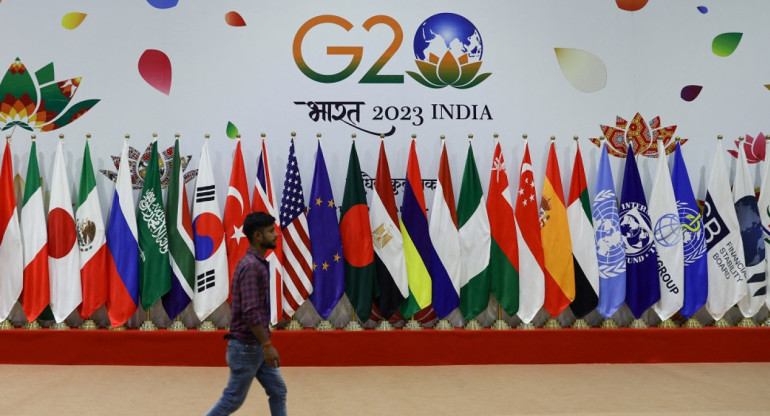 Un hombre camina cerca de banderas antes de la Cumbre del G20. Foto: Reuters.