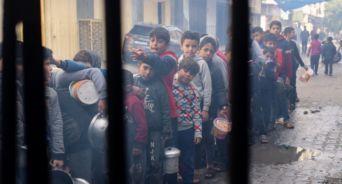 Niños palestinos esperan recibir comida cocinada en una cocina benéfica, en Rafah, Gaza. Reuters
