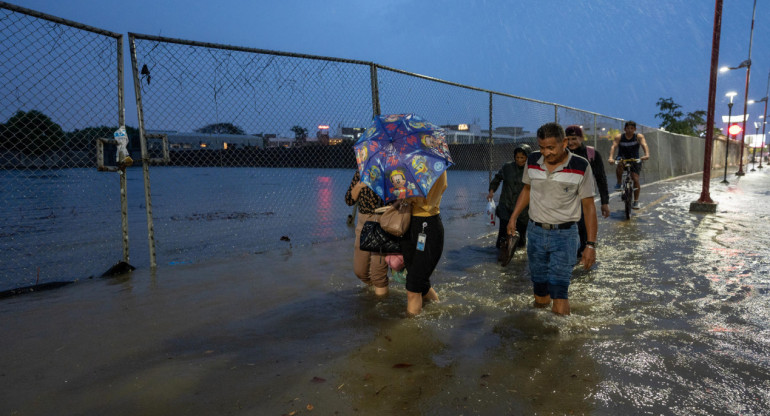 Personas caminan por una vía inundada debido a fuertes lluvias en Guayaquil, Ecuador. Foto: EFE.