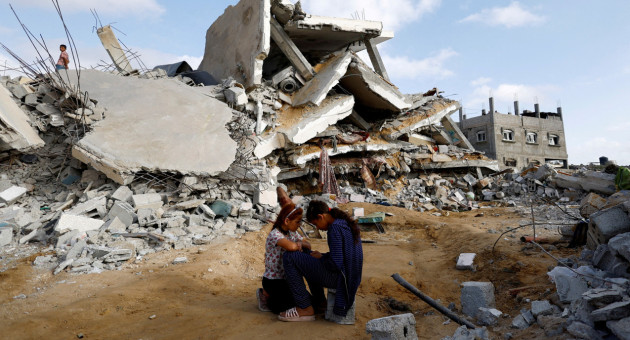 Niños palestinos sentados junto al lugar de un ataque israelí contra una casa. Foto: Reuters