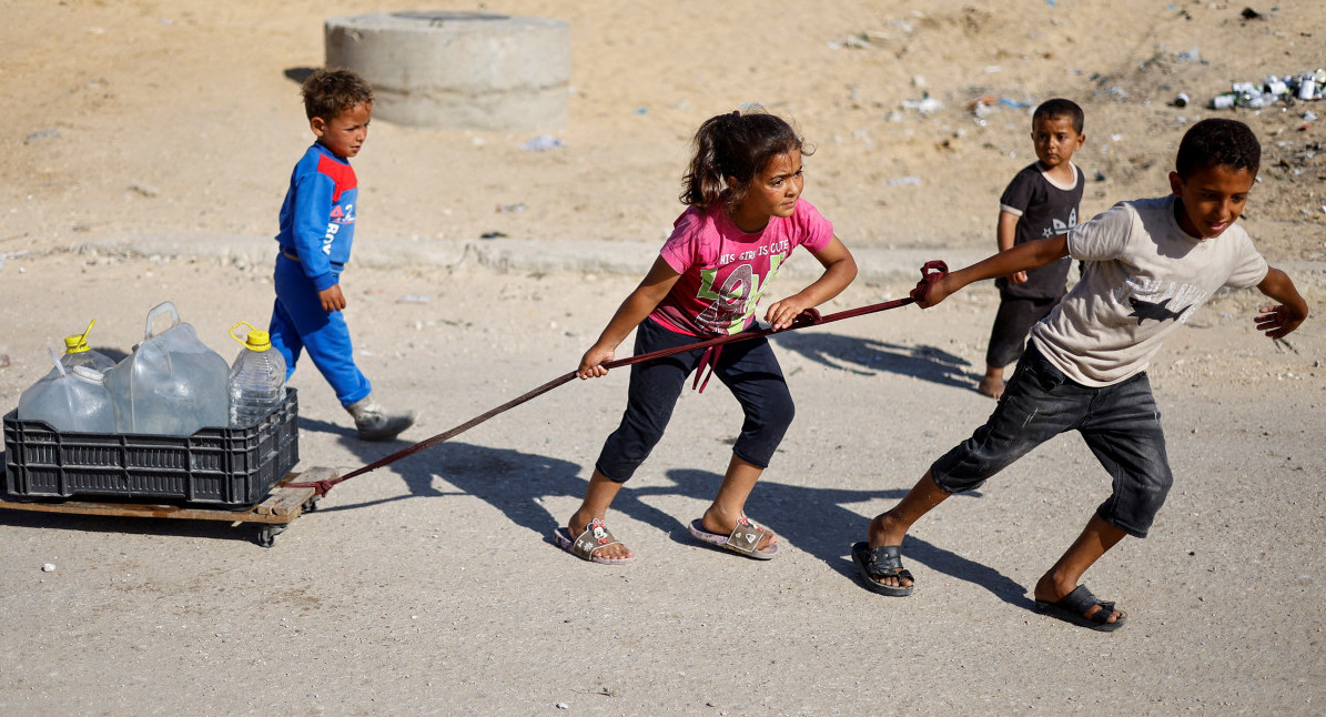 Niños palestinos llevan agua al evacuar Rafah. Foto: Reuters